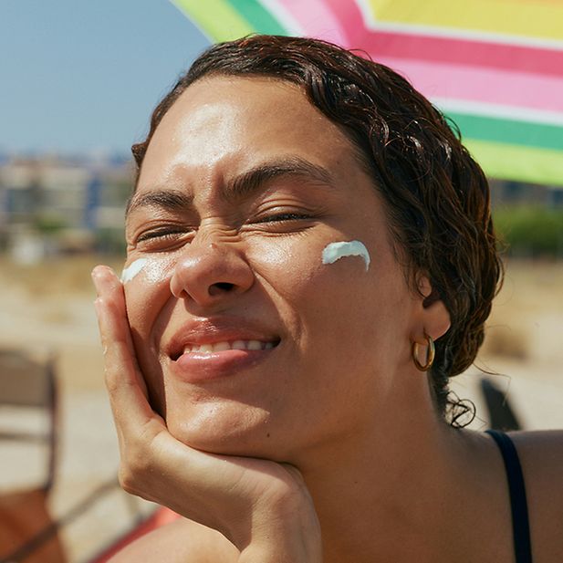 Ragazza al mare che si spalma crema solare sul viso