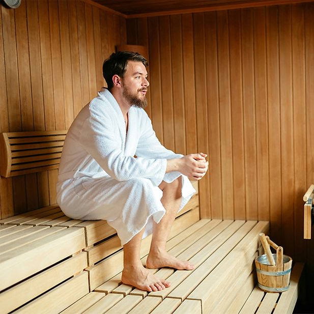 Ragazzo in accappatoio seduto in sauna