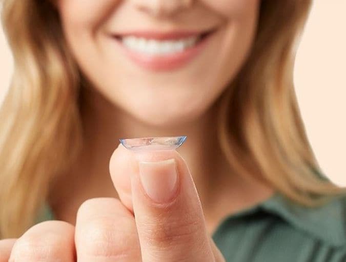 Ragazza sorridente con lente a contatto sul dito