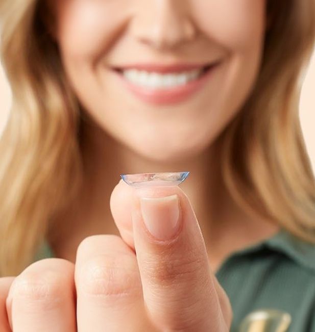 Ragazza sorridente con lente a contatto sul dito 