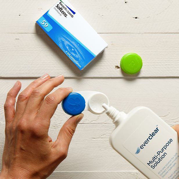 Mani che tengono un portalenti mentre viene riempito di soluzione disinfettante 