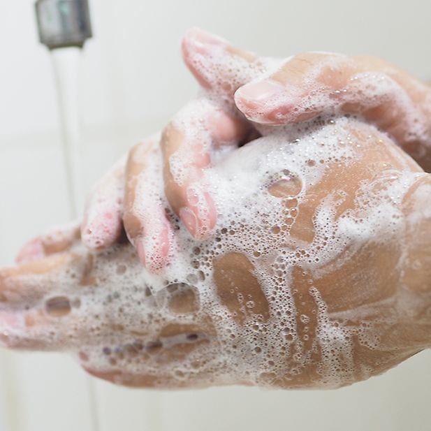 Primo piano di mani insaponate sotto il rubinetto