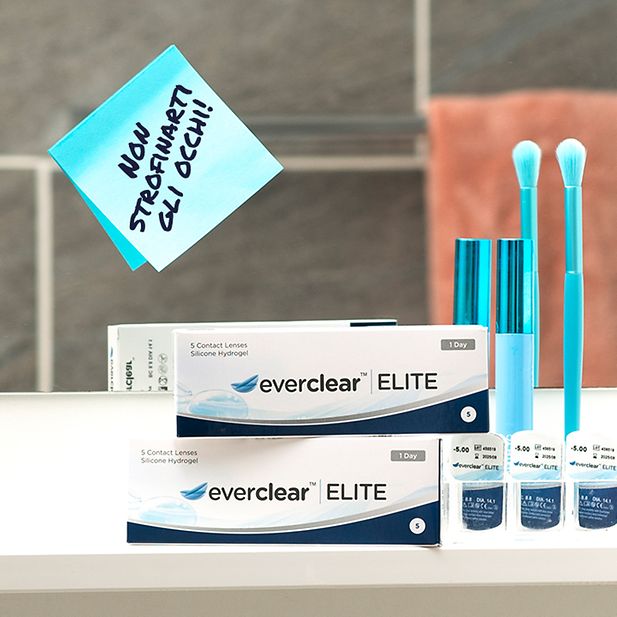 Post-it su uno specchio con su scritto “Non strofinarti gli occhi” con accanto confezioni di everclear ELITE