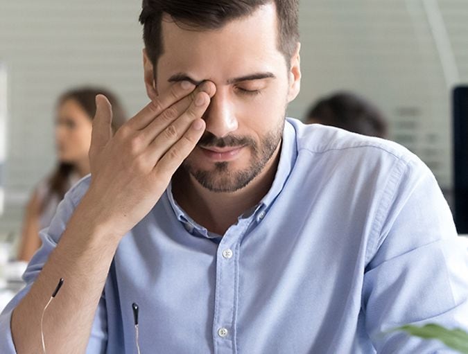 Uomo con affaticamento visivo mentre lavora al computer