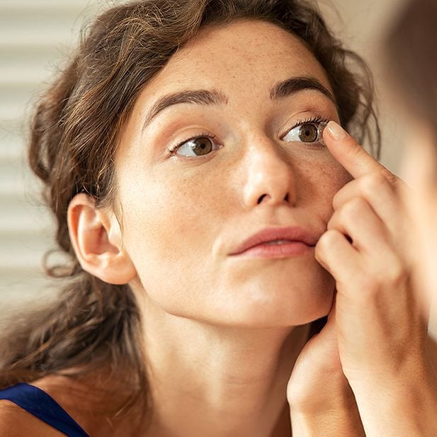 Donna che applica una lente a contatto per correggere l’ipermetropia