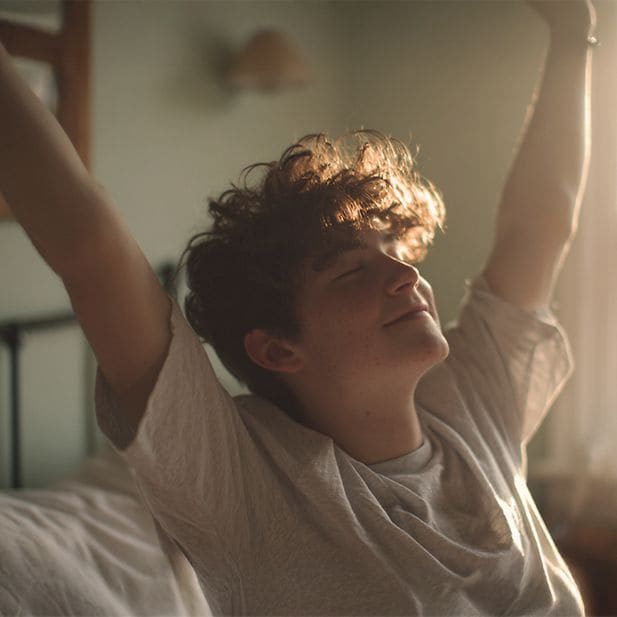 Ragazzo che si sveglia, sgranchisce le braccia e sorride