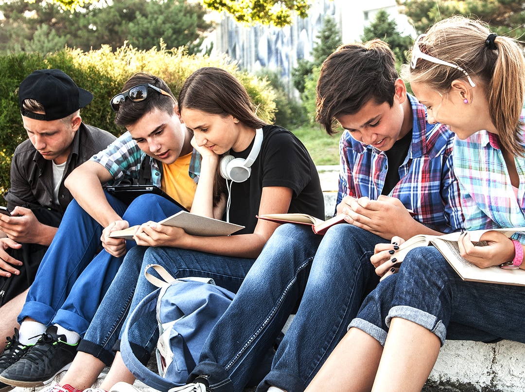 Adolescenti seduti all’aperto che leggono insieme